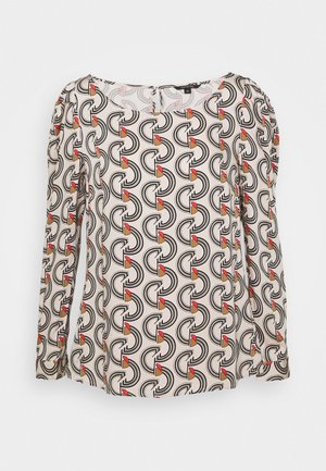 Langærmet bluse i let materiale med et gentaget geometrisk mønster i sort, creme, rød og tan, med en rund halsudskæring.