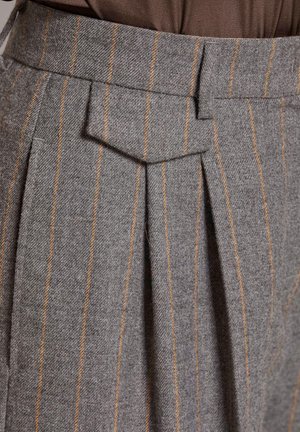 Graue Wollhosen mit orangefarbenen vertikalen Streifen, ausgestattet mit Falten und einem strukturierten Bund mit einer spitzen Klappe.