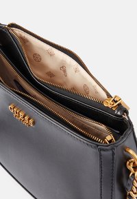 Schwarze Lederhandtasche mit goldfarbenen Beschlägen, Reißverschlussfächern und einem gemusterten Innenfutter in hellbeigen Tönen.