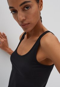 Zwart tanktop met een ronde halslijn en brede bandjes, gemaakt van gladde stof. Het ontwerp sluit nauw aan en benadrukt de schouders.