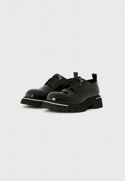 Des chaussures en cuir noir avec un bout arrondi, un design à lacets et une épaisse semelle en caoutchouc. Présentent des accents argentés et une texture lisse et brillante.