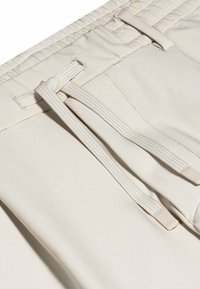 Beige lichtgewicht shorts met een platte tailleband, voorzien van een trekkoordsluiting en een gladde stofstructuur.