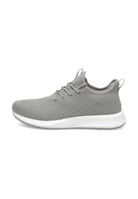 Zapatilla deportiva de color gris claro con un upper de malla texturizada, suela de goma blanca en contraste y cordones redondos. Cuenta con una pestaña en el talón.