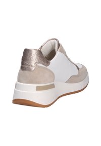 Damen-Sneaker mit einem Obermaterial aus weißem Leder, beigen Wildlederelementen, einer metallischen Ferse und einer klobigen weißen Sohle mit einem braunen Gummiprofil.