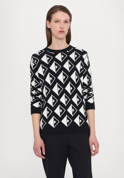 Svart og hvit genser med diamantmønster, strikket tekstur, rund hals, og ribbede mansjetter og kant. Designet er geometrisk.