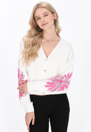 Witte cardigan met een v-hals, versierd met roze bloemenborduurwerk en zilveren accenten op de mouwen; heeft knoopsluitingen en geribbelde manchetten.