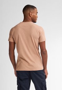 Krátký rukáv, béžové bavlněné tričko s kulatým výstřihem a hladkým povrchem, zobrazené zezadu, s volným střihem.