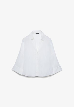Locker sitzendes weißes Hemd mit durchgehender Knopfleiste, weiten 3/4-Ärmeln und klassischem Kragen, präsentiert vor weißem Hintergrund.