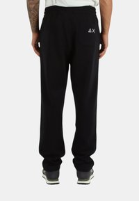 Pantaloni della tuta neri con vita elastica, tasche laterali e una tasca posteriore con dettaglio logo. Realizzati in tessuto morbido e leggero.