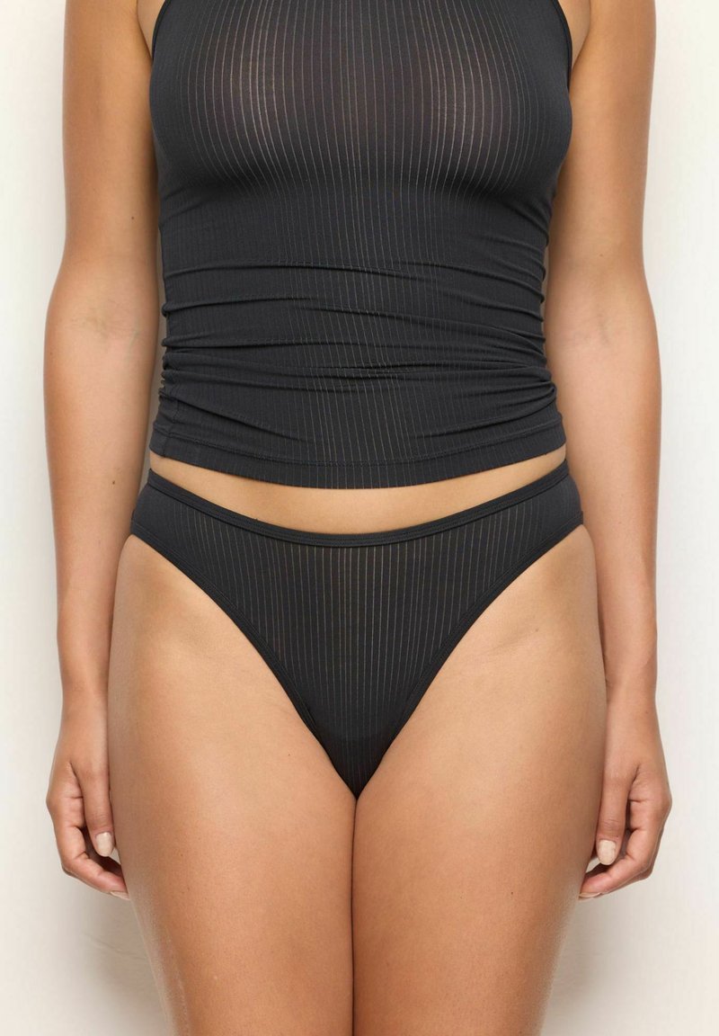 Top corto a coste nero con design aderente, abbinato a slip bikini a coste a vita alta. Entrambi gli articoli presentano una texture morbida e una finitura elegante.