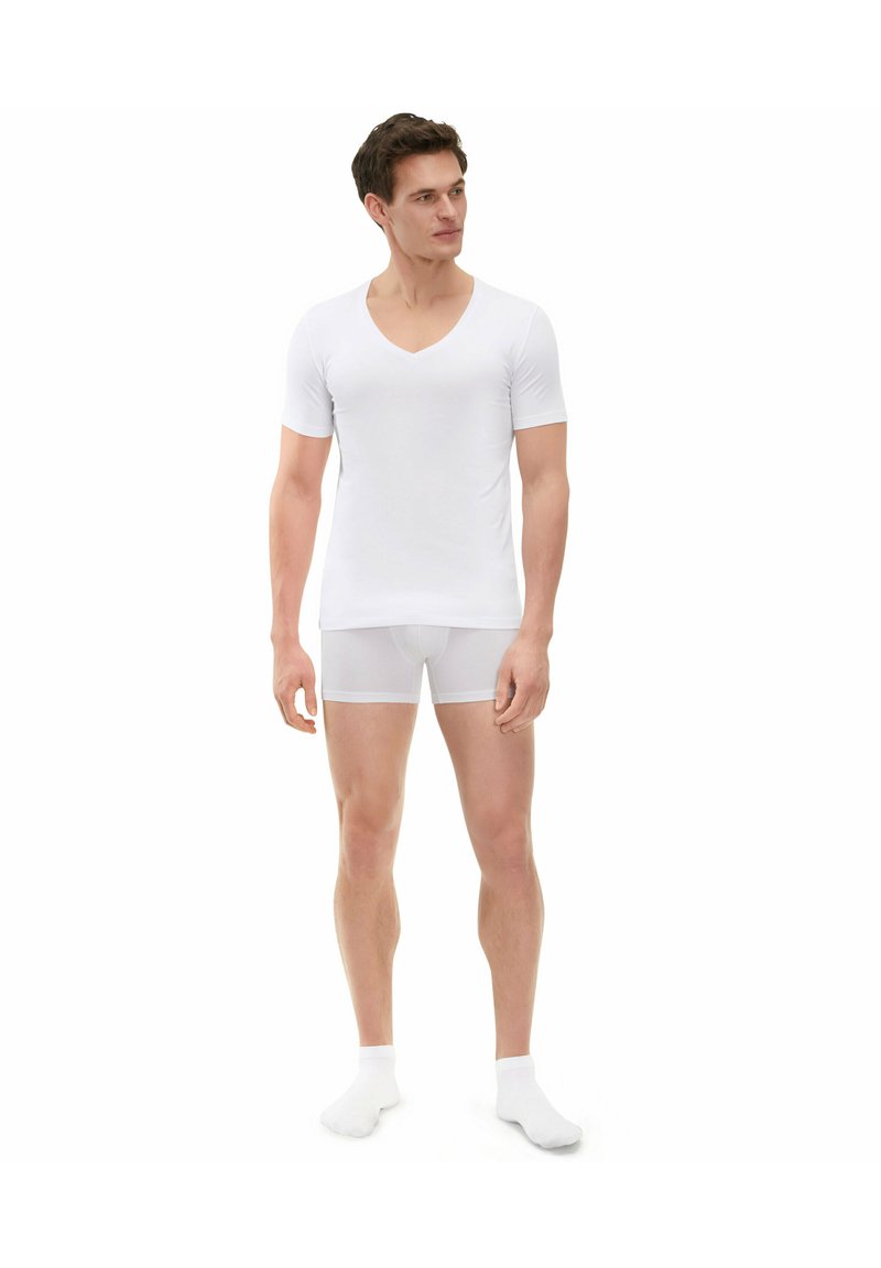 White short-sleeve V-neck t-shirt paired with white fitted shorts. Smooth fabric with a simple design, showcasing clean lines and minimal texture.