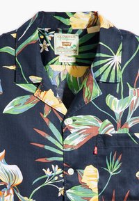 Kurzärmeliges navy-blaues Blusenshirt mit leuchtend gelben und grünen tropischen Mustern, einem klassischen Kragen und einer einzelnen Tasche mit einem roten Levi's-Tag.