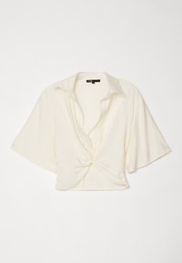 Blouse crème à manches courtes avec manches larges, col ouvert et détail nœud torsadé à l'avant, étalée à plat sur une surface blanche.