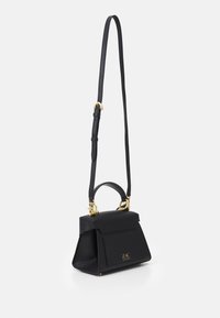 Borsa a mano in pelle nera con manico superiore e tracolla regolabile, dettagli in oro, e tasca frontale decorata con "ZAC ZAC POSEN."