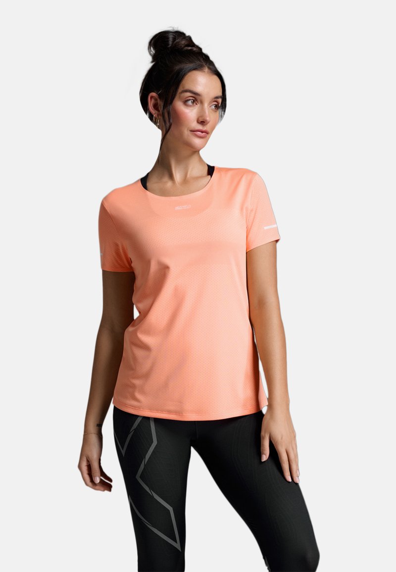 Korte mouwen, lichtgewicht, ademend performance T-shirt in helder koraal met een stippenstructuur, gecombineerd met zwarte leggings met geometrisch patroon.