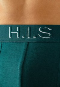 Zelena moška spodnja perila iz mehkega, strukturiranega blaga. Ima kontrastni vezeni bel logo "H.I.S." na pasu.