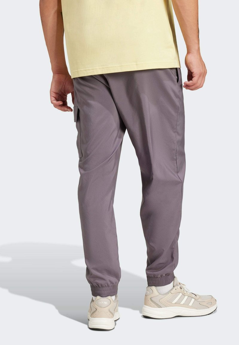 Joggers ligeros y grises con puños elásticos y bolsillos laterales, combinados con zapatillas beige que cuentan con rayas blancas y un diseño texturizado.
