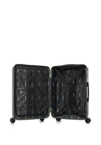 Otevřený zelený tvrdý kufr s černým a šedým vnitřním potahem, elastické křížové popruhy na jedné straně, zipové kapsy na druhé straně a čtyři kolečka.