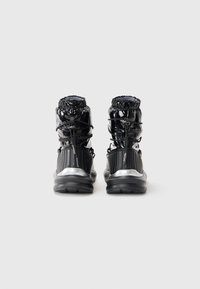 Black high-top sneakers with a glossy finish, ribbed texture, elastic laces, and silver accents on the sole and heel.