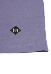 Lyslilla bomulds t-shirt med et sort diamantformet logo, der har et hvidt "H" og "R" broderet i nederste venstre hjørne.
