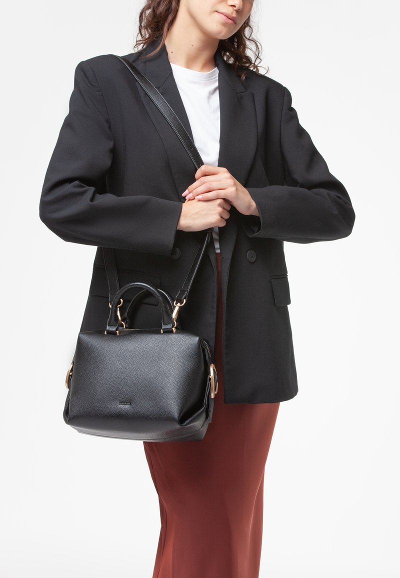 Sorte struktureret taske med en tekstureret overflade, dobbelt topstænger og en aftagelig skulderrem. Guldtonede hardwaredetaljer er synlige.