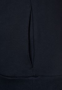 Marineblauwe sweatshirtstof met een zijzak en geribde zoom, met een gladde textuur en zonder zichtbare patronen of versieringen.