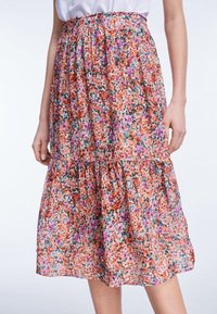 Gonna midi floreale in stampe arancioni, rosa e verdi. Tessuto leggero e fluido con vita elastica arricciata e design a strati.