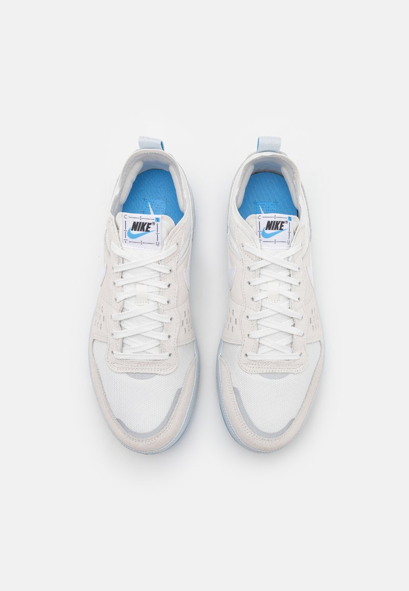 Zapatillas blancas de Nike con parte superior de malla y ante, acentos en azul claro, lengua acolchada y cordones planos. Presenta detalles perforados para una mayor transpirabilidad.