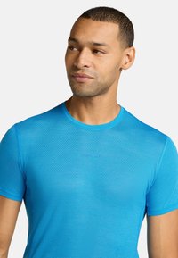 Camiseta atlética de manga corta en color azul, hecha de un material texturizado y que absorbe la humedad. Presenta un escote redondo y un logotipo sutil en el frente.