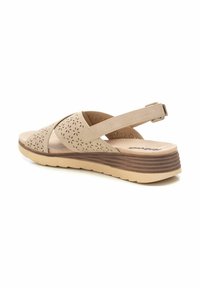 Sandalia beige con parte superior perforada y diseño de tiras cruzadas. La plantilla acolchada y la suela texturizada ofrecen comodidad y estabilidad.