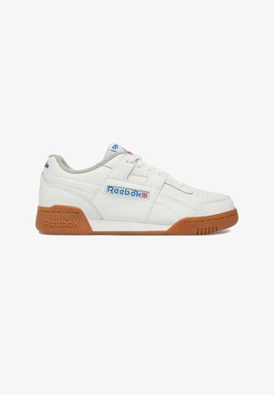 Zapatilla blanca Reebok de corte bajo con suela de goma, logo azul de Reebok y Union Jack en el lateral, forro interior gris y parte superior de cuero cosido.