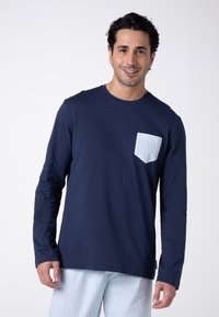 Camicia a maniche lunghe blu navy con taschino a righe azzurre. Tessuto morbido, design a girocollo, vestibilità comoda. Abbinata a pantaloni a righe azzurre.