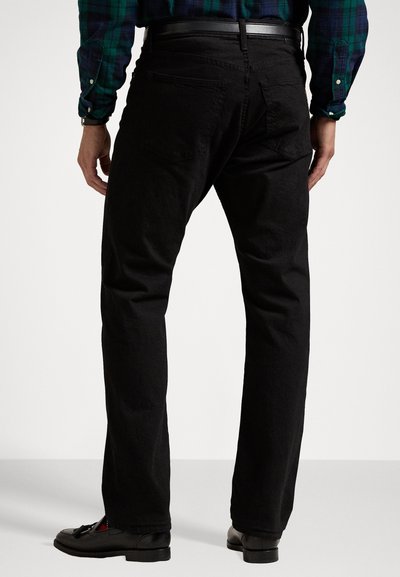 Black denim pants feature a straight leg design, five-pocket styling, subtle texture, and a standard waistband. Worn with black shoes.