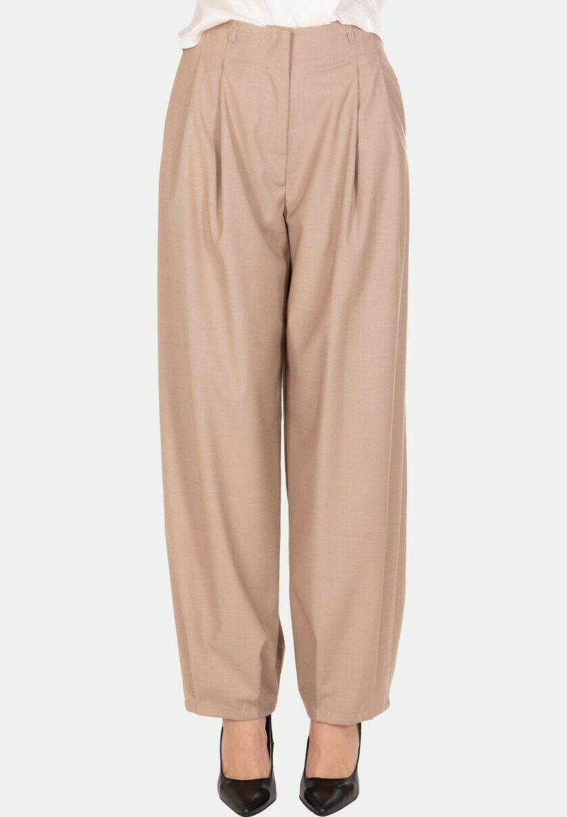 Pantaloni beige a vita alta con pieghe e gamba larga abbinati a décolleté nere con punta a punta, indossati con una maglia bianca infilata.