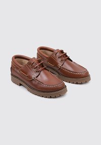 Zapatos de cuero marrón con un acabado suave, diseño de cordones, costuras en contraste y suela de goma texturada, con punta redondeada y cuello acolchado.