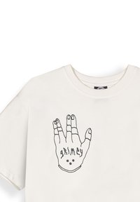 Camiseta de algodón blanca con un gráfico de un contorno negro de una mano con la palabra "grimey" y dos puntos impresos. Manga corta, escote redondo.