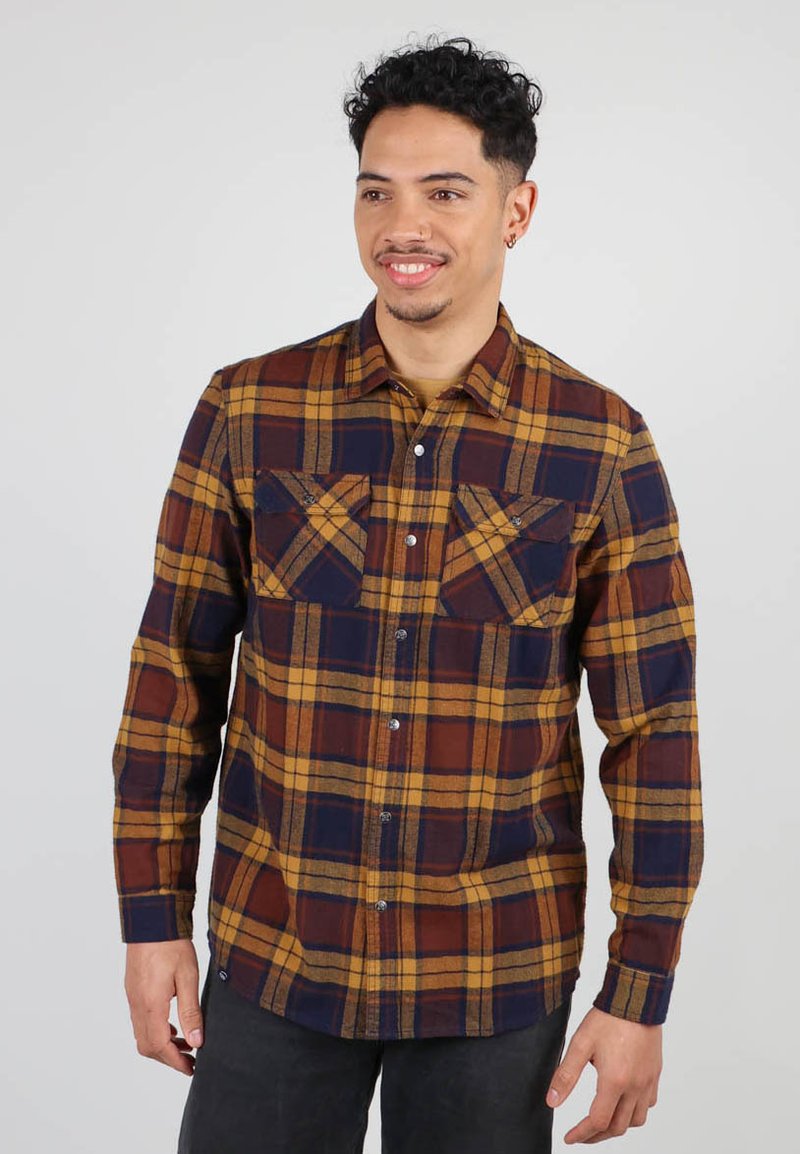 Chemise en flanelle à carreaux pour homme, dans des tons de bleu marine, moutarde et rouille. Dotée de manches longues, de deux poches poitrine et d'une fermeture à boutons. Texture de tissu douce.