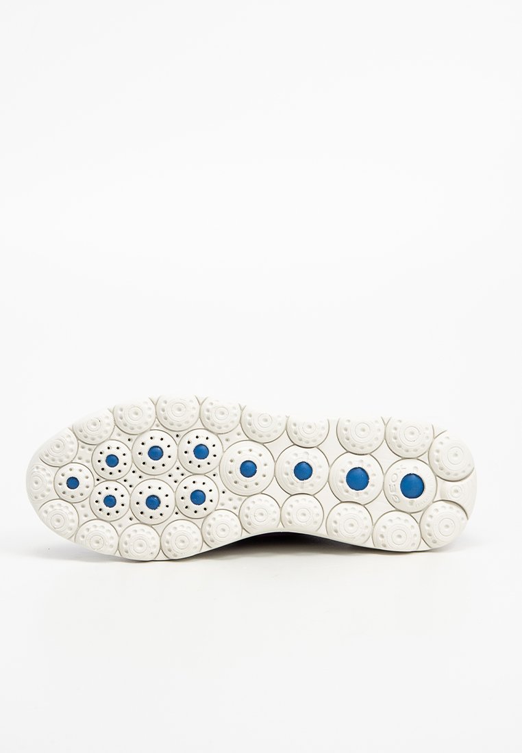 Suola di una sneaker bianca con motivo circolare, caratterizzata da centri blu e piccole perforazioni, fotografata su uno sfondo bianco.