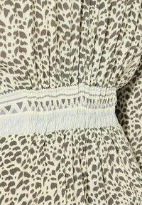 Leopardí vzor tkaniny v béžových a hnědých tónech, s elastickým pásem a jemným pruhovaným detailem ve světle levandulové barvě.