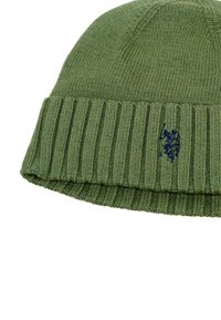 Pletená čiapka olivovej zelenej farby s rebrovaným lemom. Na leme je vyšitý tonálny logotyp polo v námořníckej farbe. Mäkká textúra, zaoblený tvar.