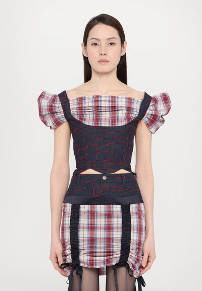 Sculpted top with plaid puff sleeves and a dark denim base, featuring red thread accents; paired with a ruched plaid skirt and ties.