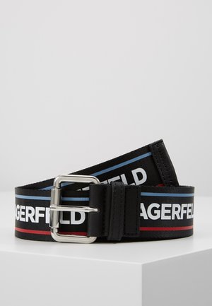 Ceinture en tissu noire avec boucle argentée, comportant un texte blanc en gras et des bandes horizontales bleues et rouges sur la lanière.