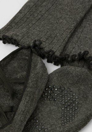 Leggings grigi in maglia con bordi arricciati e un paio di calzature simili a calze abbinate, caratterizzate da una suola testurizzata e con grip migliorato.