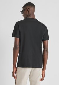 Camiseta de algodón negra con mangas cortas, cuello redondo y un ajuste relajado. La tela parece suave; no hay patrones ni logotipos visibles.