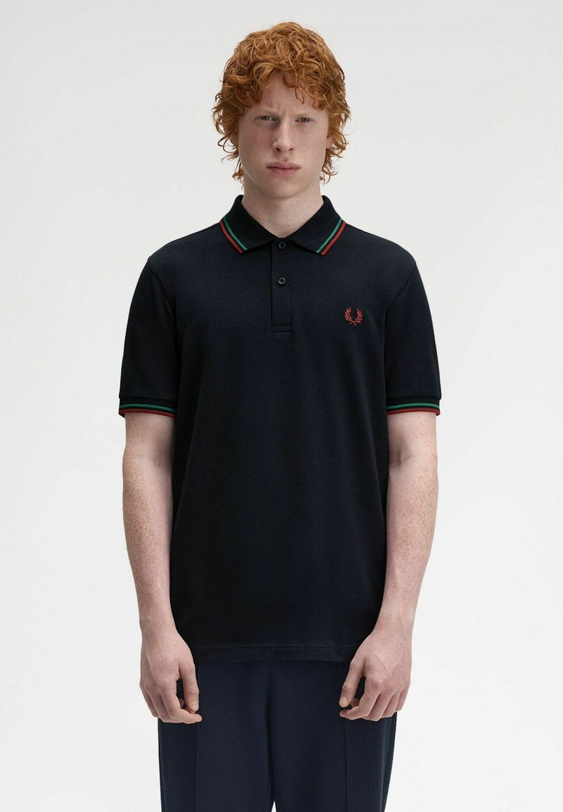 Polo shirt nera con una patta a tre bottoni, colletto e polsini a righe rosse e verdi, con un piccolo logo ricamato sul petto.