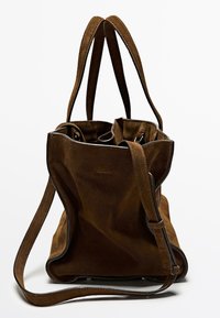 Sac fourre-tout en daim brun avec double poignée et bandoulière réglable ; présente une texture douce et un design à ouverture sur le dessus. Aucuns détails matériels visibles.