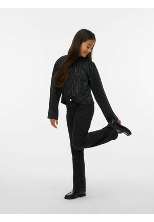 Juoda ilgomis rankovėmis palaidinė su sidabrinėmis linijiniais raštais, suderinta su juodais prigludusiais džinsais ir juodais batais. Modelis pozuoja pakėlęs vieną koją.