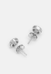 Silver stud earrings with a round design, featuring a textured edge and a smooth center. Includes a post and butterfly back closure.