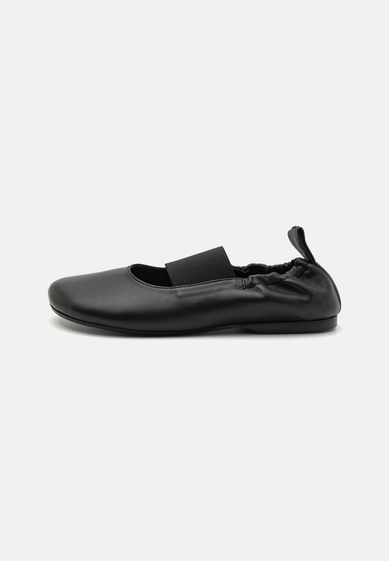 Chaussure plate en cuir noir avec une bride élastique sur le dessus et une section de talon froncée dotée d'une languette à l'arrière.