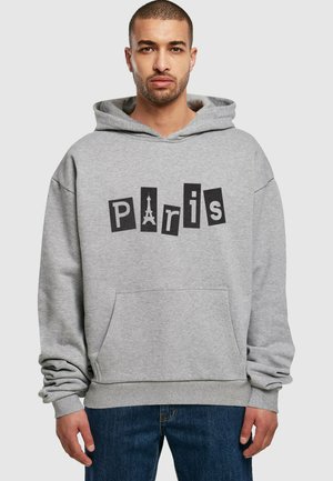 Grå hættetrøje med ordet "Paris" i sorte bogstaver, med et grafisk billede af Eiffeltårnet som en del af bogstaverne. Foran er der en kængurulomme.